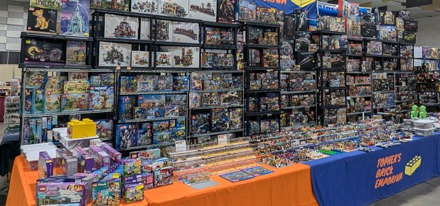 Vendor tables stacked with LEGO sets and minifigures in the vendor hall